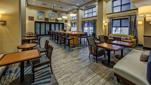 A hotel lobby with a bar area, seating arrangements, and large windows providing natural light. - Hampton Inn & Suites Stuart-North (Stuart)