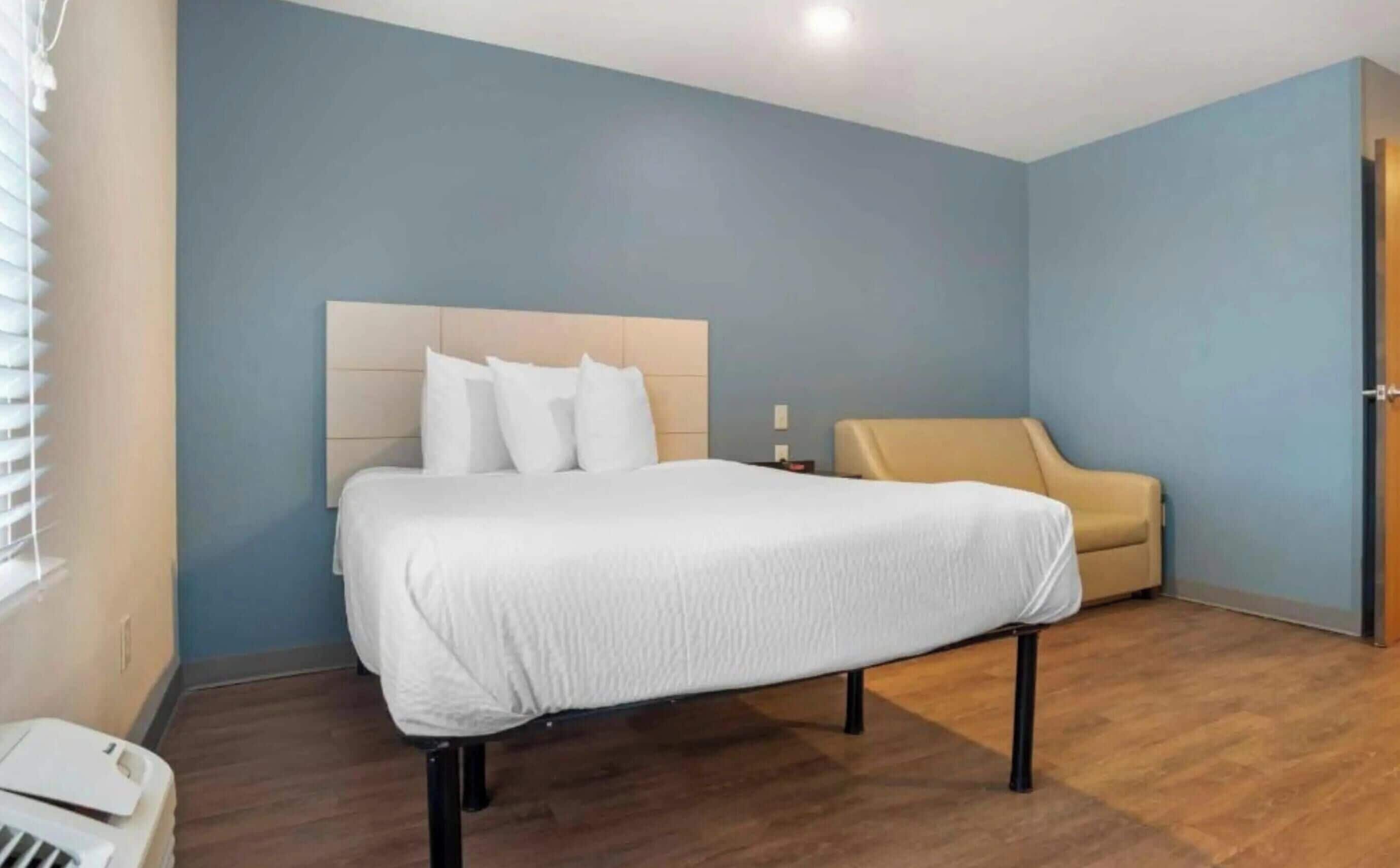 A hotel room with a bed, a sofa, and a wooden floor.