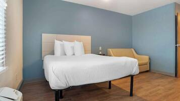 A hotel room with a bed, a sofa, and a wooden floor.