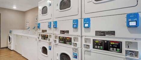 A laundry facility with multiple washing machines and dryers, each with control panels and numbered tags.