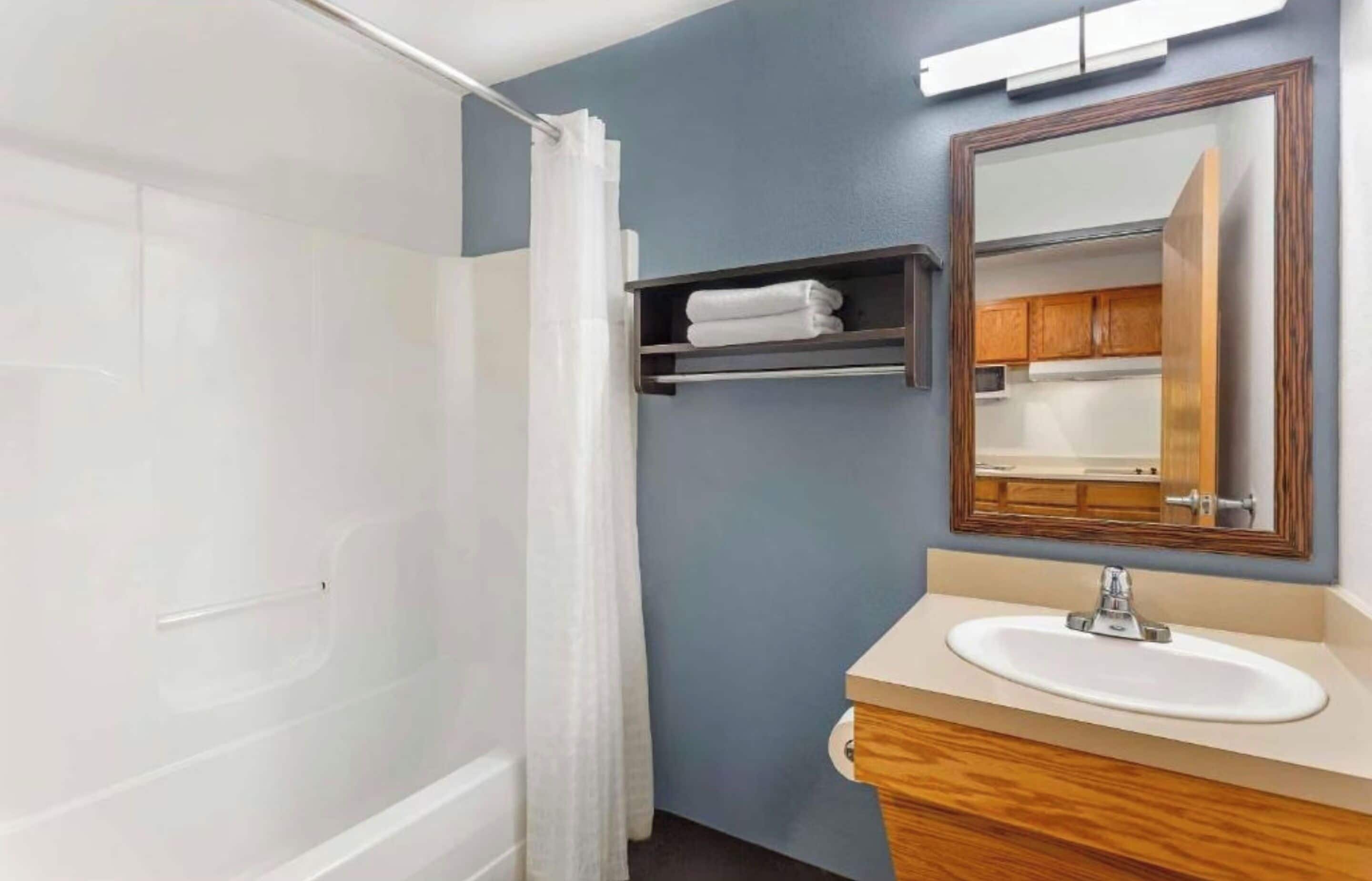 Un baño con bañera, lavamanos, espejo y perchero para toallas.