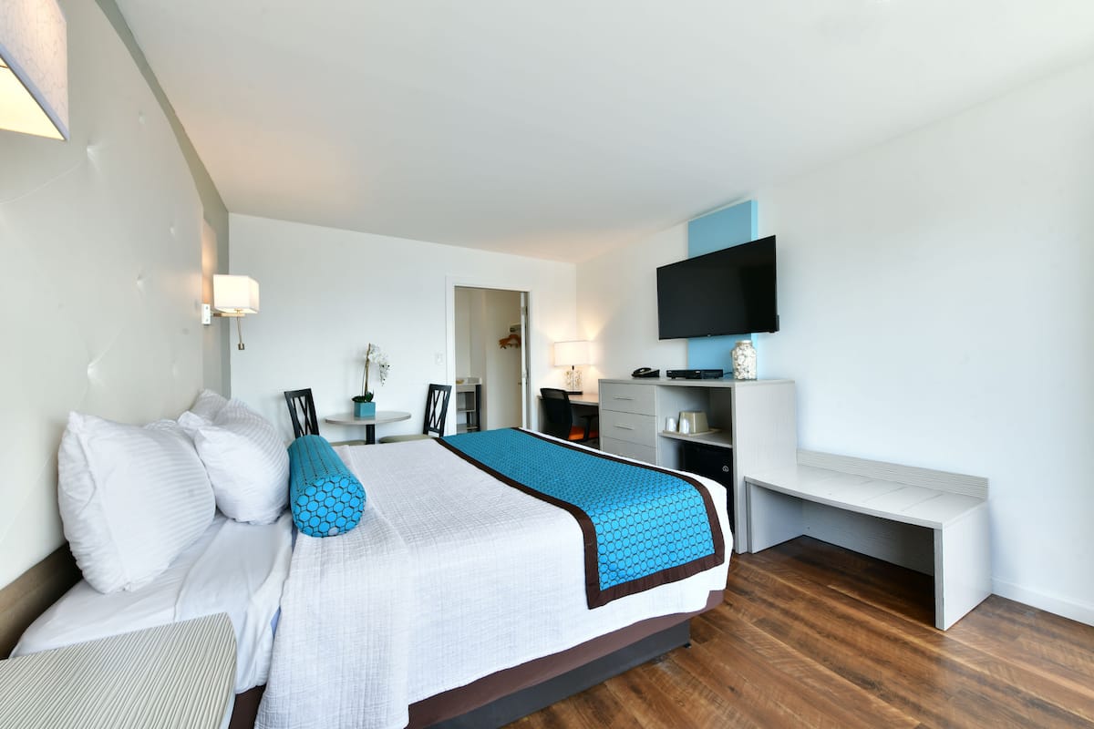 Ein modernes Hotelzimmer mit einem großen Bett, einem Schreibtisch, einem Sessel, einem Fernseher und einer Bank.