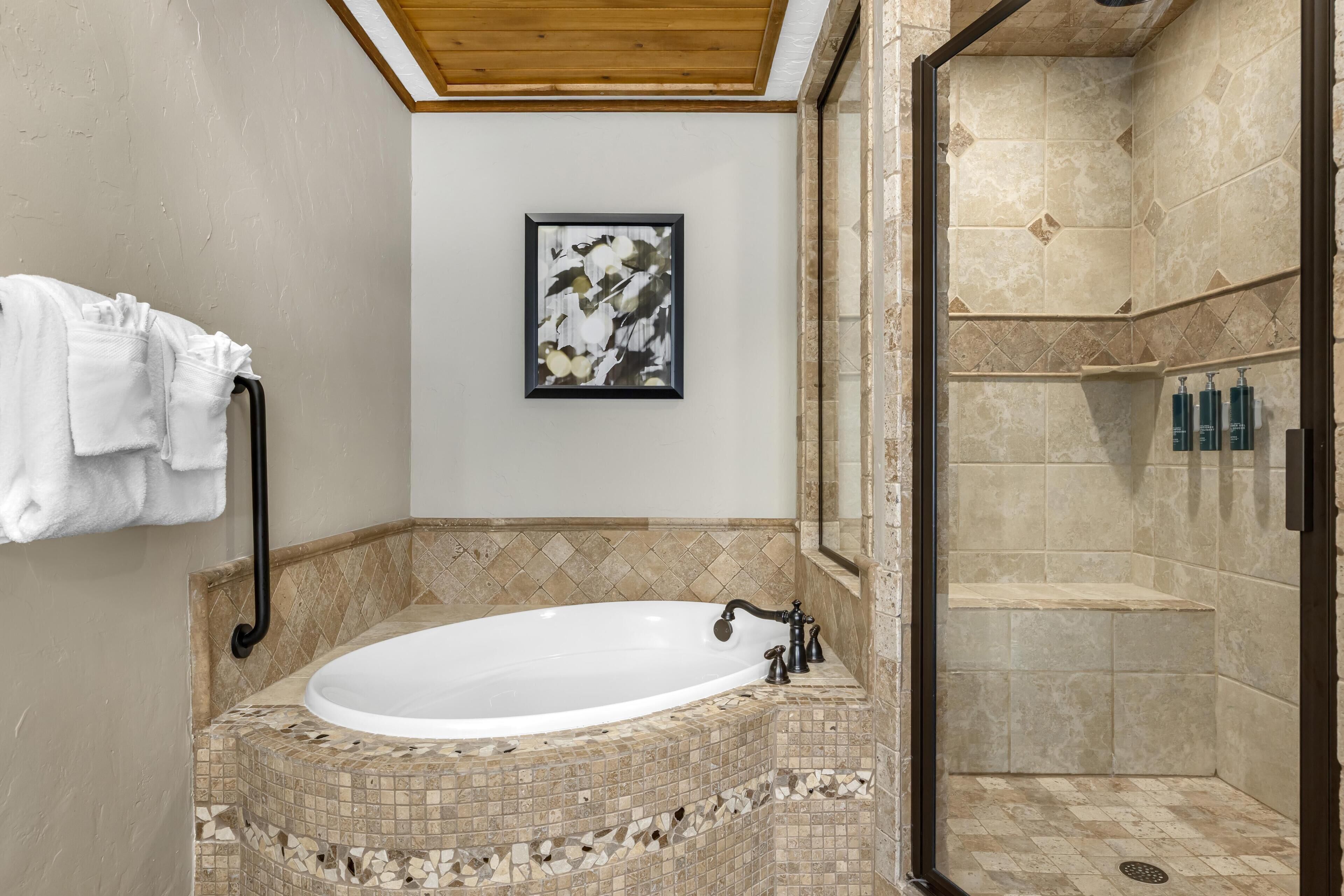 A bathroom with a freestanding bathtub, a shower area, and a framed artwork on the wall.