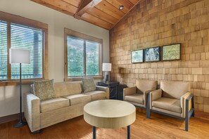 A living room with a wooden ceiling, a sofa, two armchairs, a round coffee table, and a wall with framed artwork. - Hilton Grand Vacations Club Stonewater Cove Shell Knob (Shell Knob)