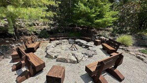 A circular seating area with benches and a central fire pit surrounded by rocks.