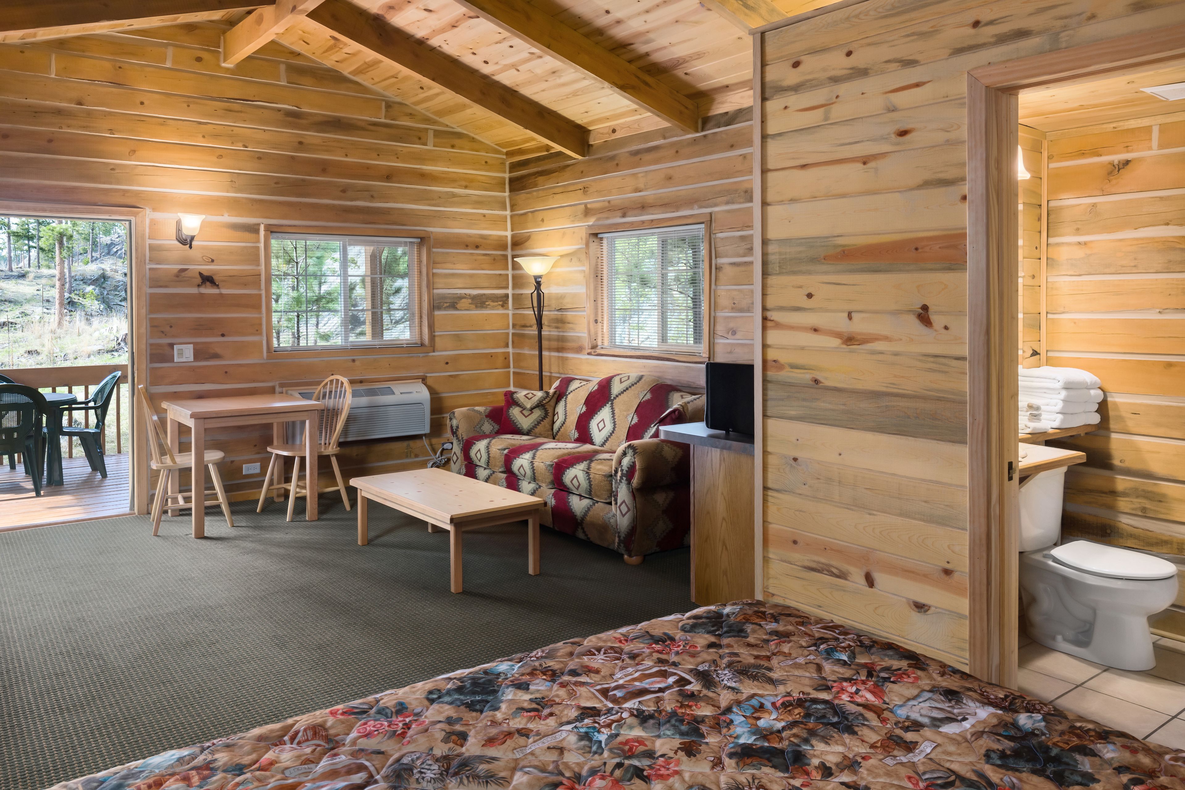 Une chambre aménagée dans un chalet en rondins, avec un lit, un canapé, un bureau et une chaise.
