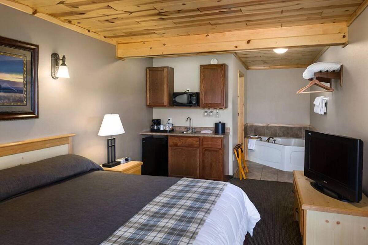 Una camera da letto con un letto, una lampada da comodino e una televisione su un supporto in legno.