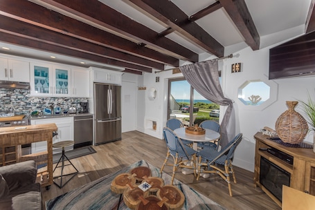 A modern kitchen with white cabinets, a stainless steel refrigerator, and a wooden dining table with blue chairs.. Beachcomber Resort at Montauk