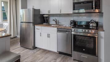 A modern kitchen with stainless steel appliances, white cabinetry, and a granite countertop.