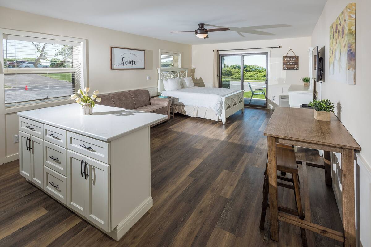 A spacious room with a large bed, a desk, and a kitchenette.