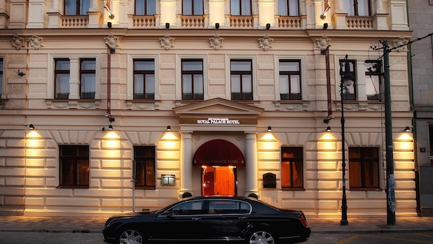 A historic building with a classic facade, a prominent entrance, and a black car parked in front.