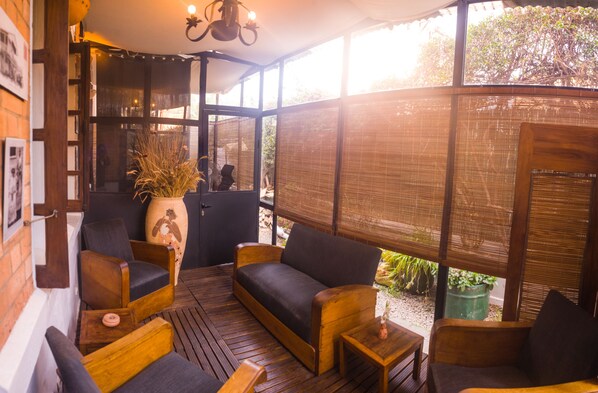 A cozy outdoor seating area with wooden furniture and a large vase.