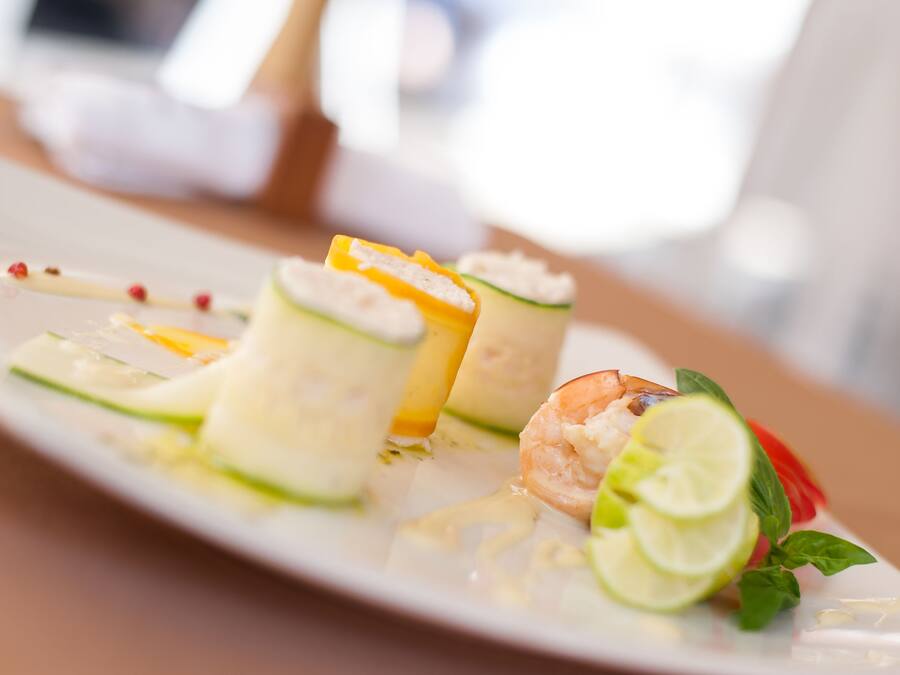 Un plato de comida con camarones, pepino y gajos de limón.