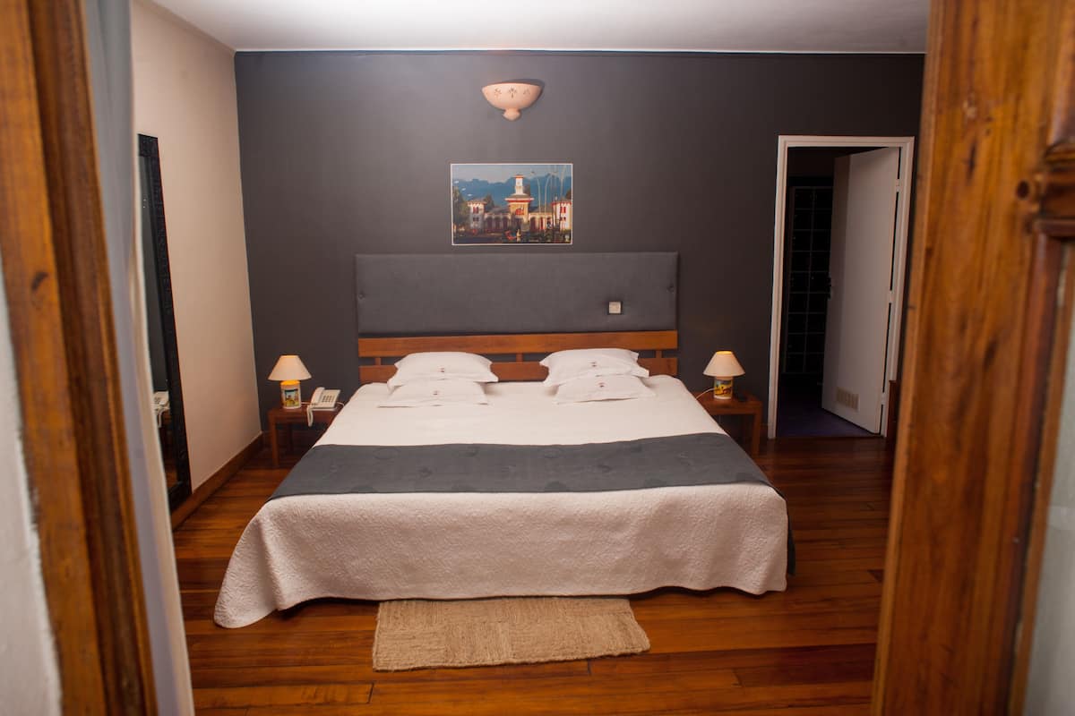 A neatly made bed with a white and gray bedspread, a wooden headboard, and two bedside lamps.