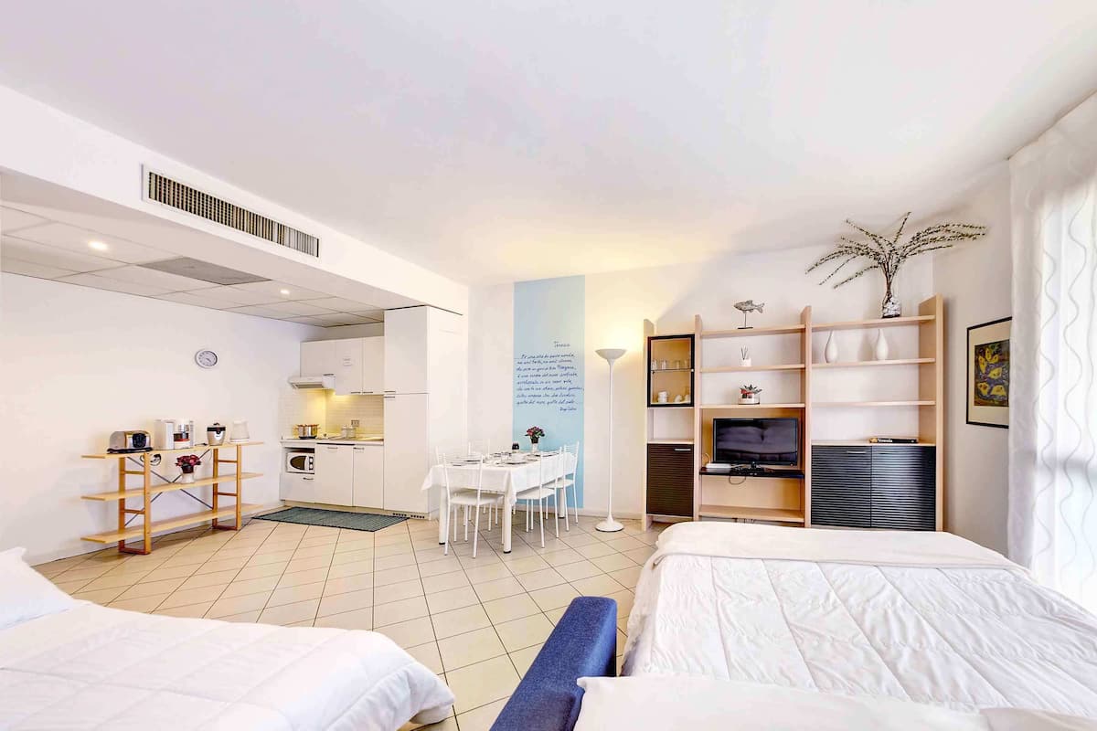 A hotel room with two beds, a kitchenette, a dining area, and a TV.
