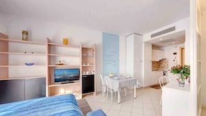 A modern hotel room with a bed, TV, dining area, and kitchenette. - Residence Venice (Quarto d'Altino)
