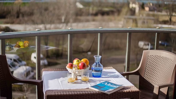 A balcony with wicker chairs, a table with a basket of fruit, a vase, and a bottle of water. - Residence Venice (Quarto d'Altino)