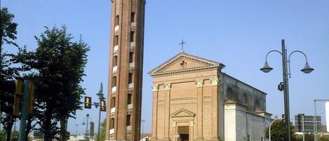 Una iglesia con un campanario alto y un edificio más pequeño con un frontón.