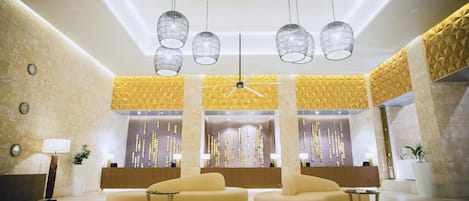 A modern lobby with a reception desk, two sofas, and hanging pendant lights.