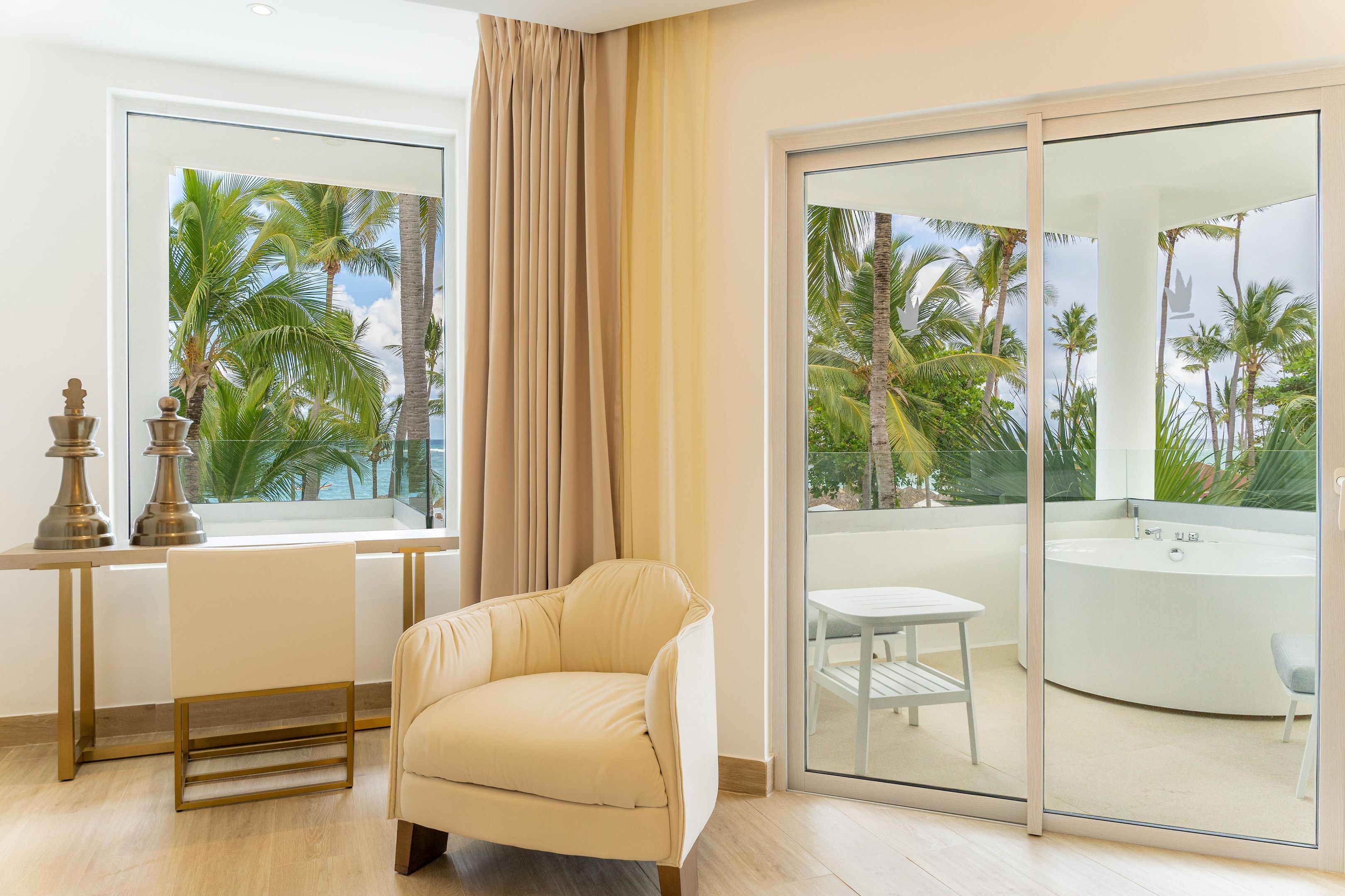 A modern room with a large sliding glass door leading to a balcony with a view of palm trees and a hot tub.