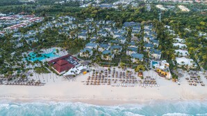 An aerial view of a resort with multiple buildings, a beach, and a swimming pool.