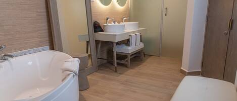 A modern bathroom with a large bathtub, two sinks, and a vanity with a mirror.