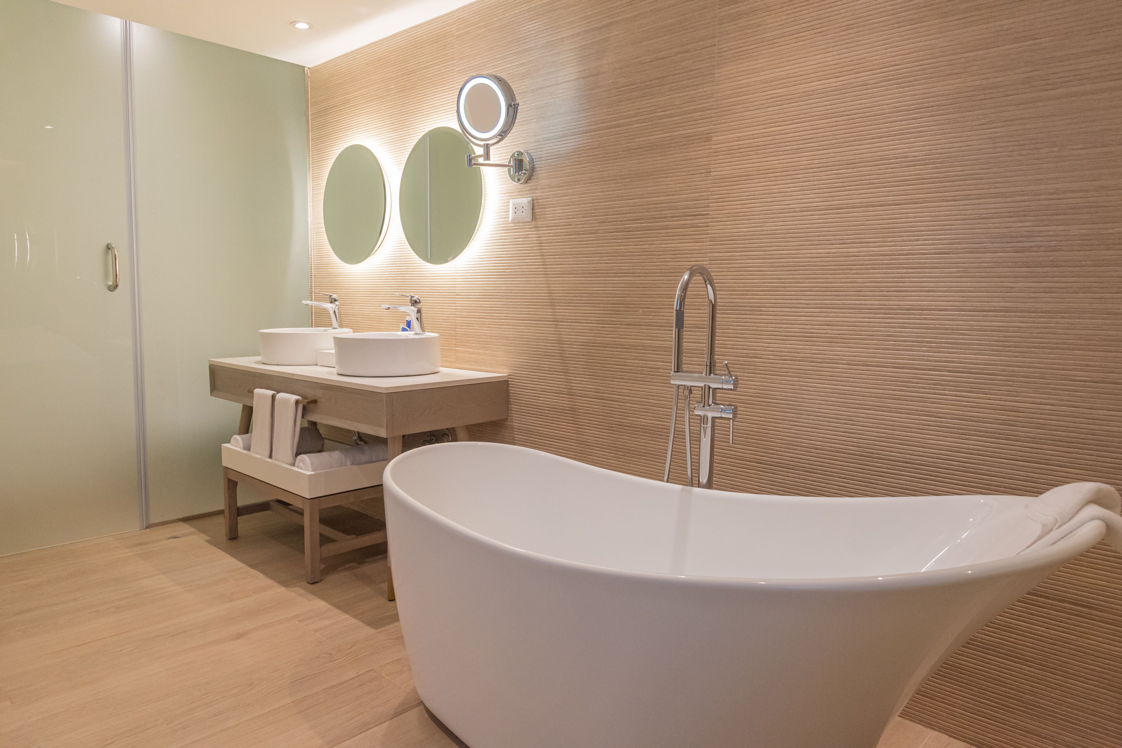 A modern bathroom with a freestanding bathtub, two round mirrors, and a vanity with a sink.