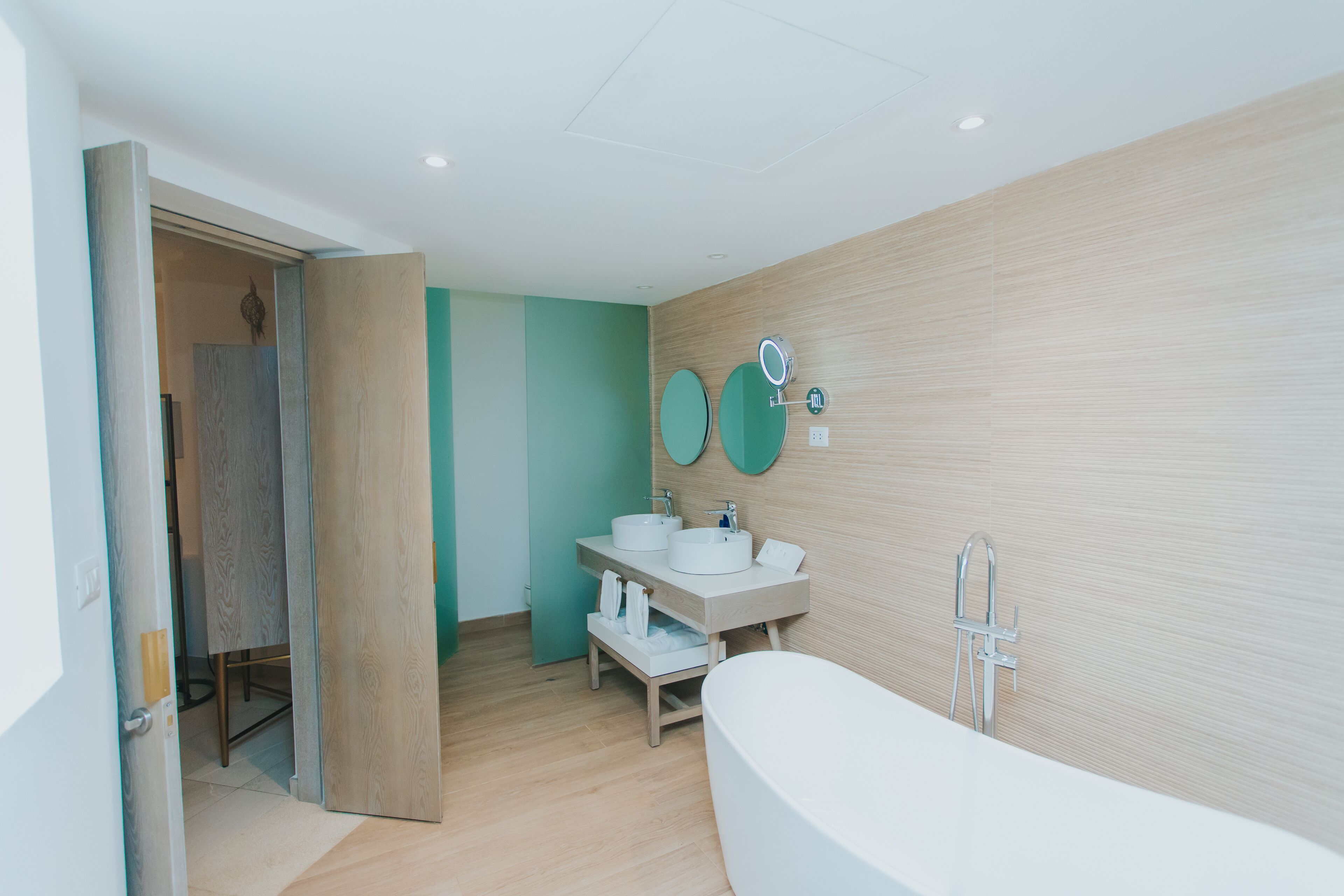 Een moderne badkamer met een vrijstaand bad, twee wastafels en een spiegel.