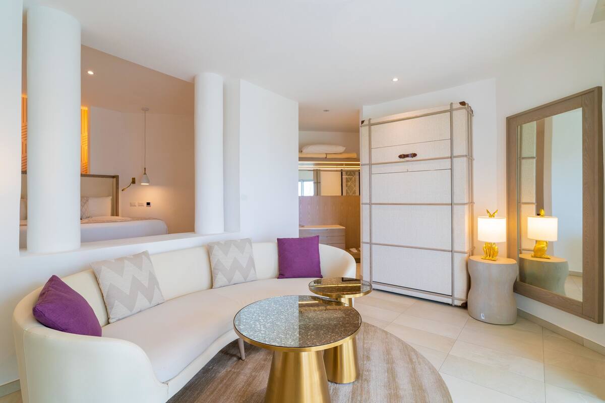 A modern living room with a white sofa, a round coffee table, and a glass partition.