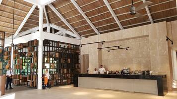 A spacious bar area with a high ceiling and wooden beams, featuring a counter with various bottles and glasses.
