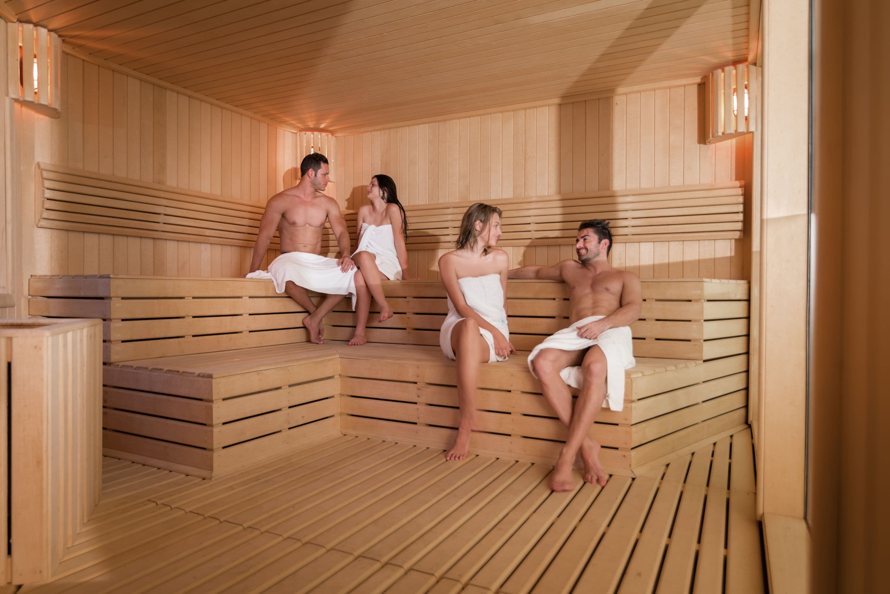 A sauna with wooden benches and benches, and a person sitting on a bench.