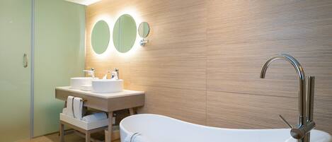 A modern bathroom with a freestanding bathtub, a vanity with a mirror, and a wooden wall panel.