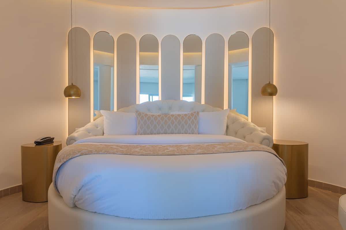 A modern bedroom with a large bed, two bedside tables, and a unique wall design with vertical panels.