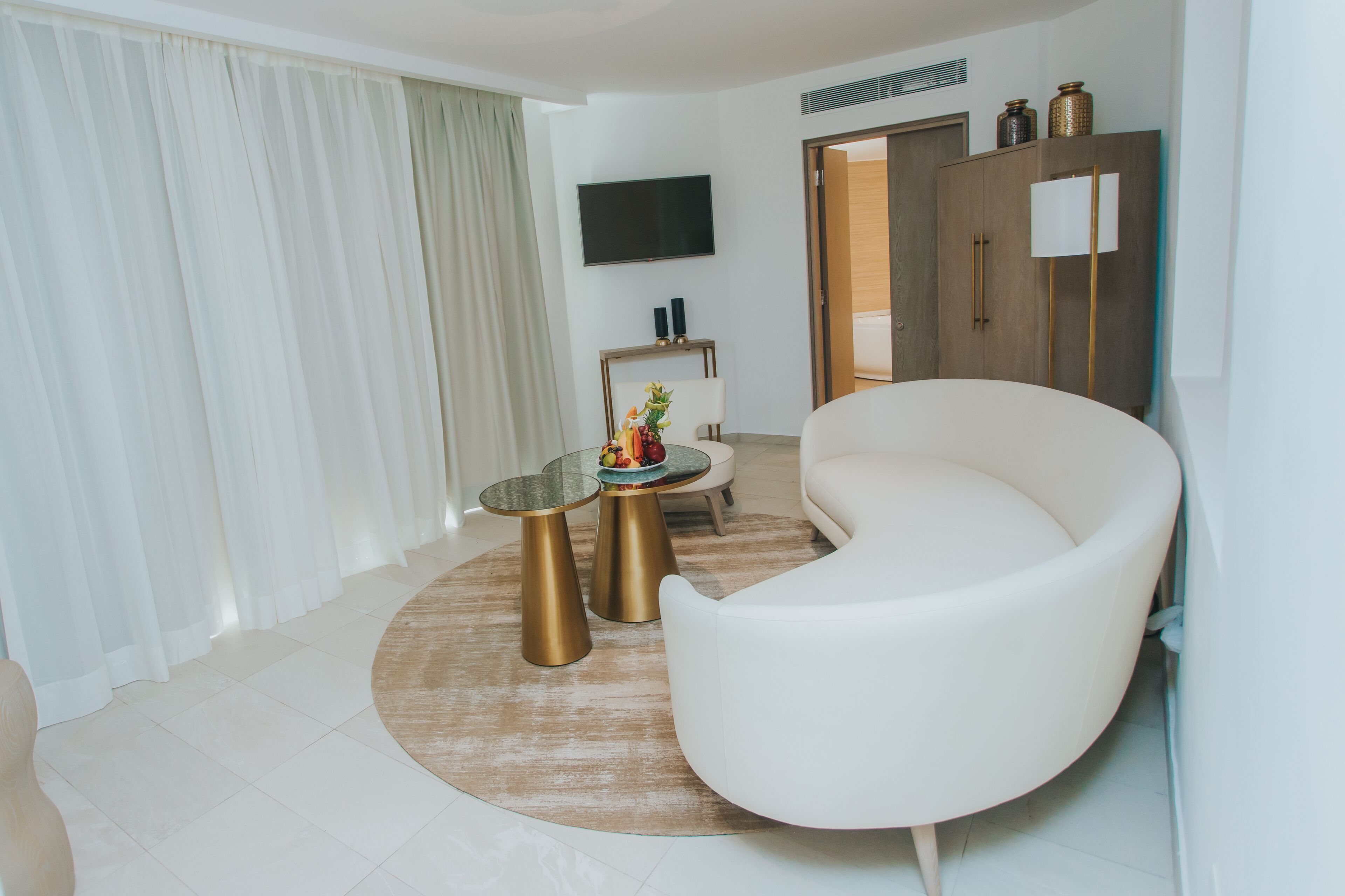 A modern living room with a white sofa, a glass coffee table, and a round rug.