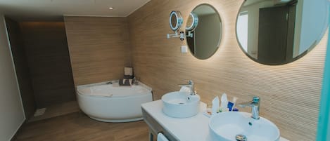 A modern bathroom with a large bathtub, two sinks, and a mirror.