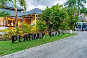 En hotellentrén med en skylt som visar texten ”PLATINUM PRINCESS” och en asfalterad gångväg som leder fram till byggnaden.