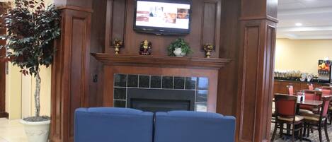 Un hall con chimenea, un televisor montado encima y zonas de estar.