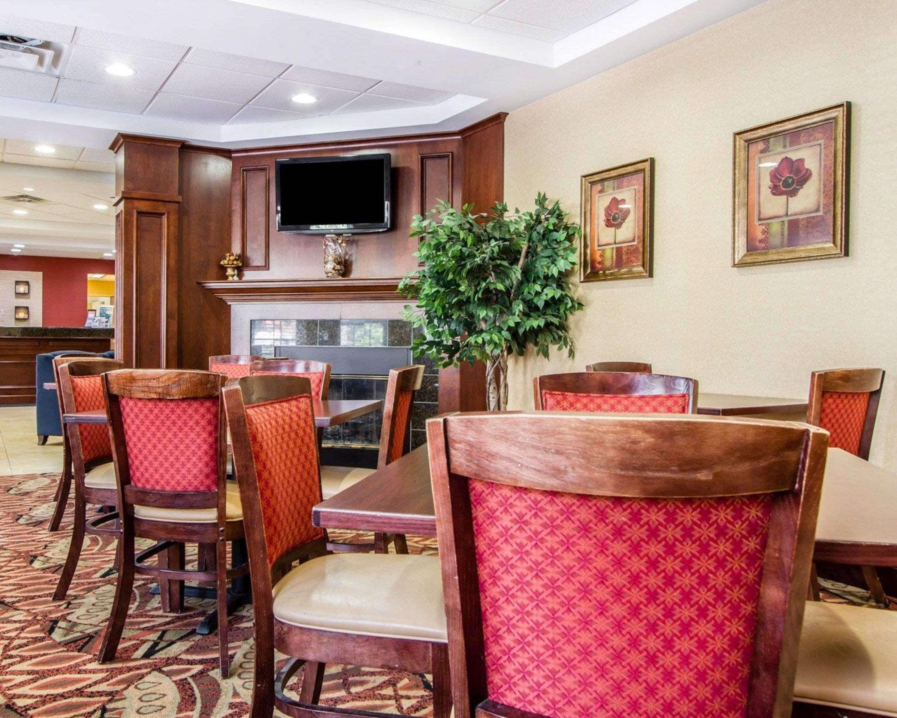 Un comedor de hotel con mesas y sillas de madera, un televisor de pantalla plana y cuadros en la pared.