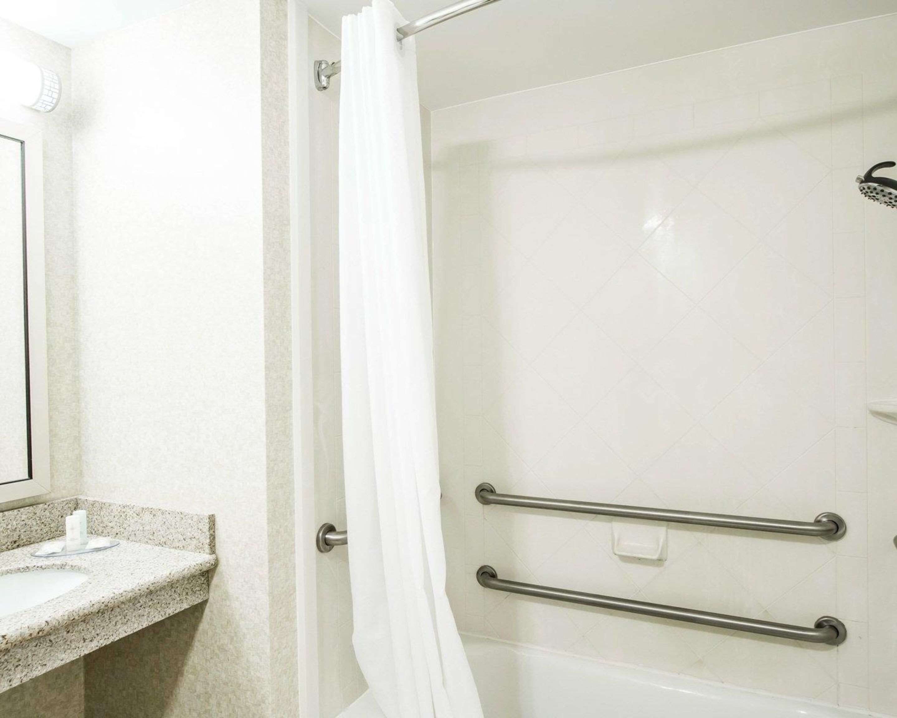 A bathroom with a shower, a sink, and a mirror.
