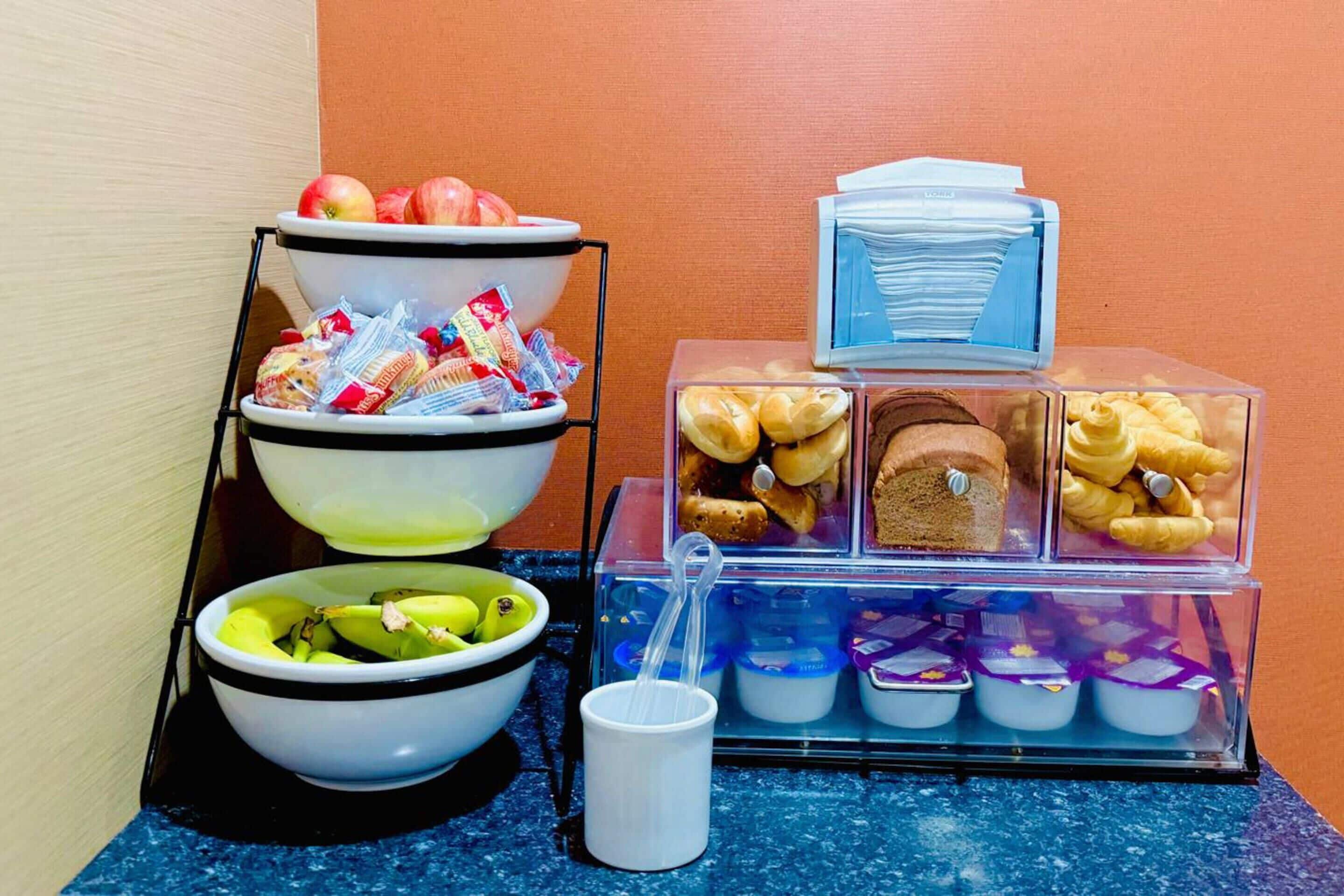 Un bufé de desayuno con tazones de fruta, pasteles y alimentos envasados.