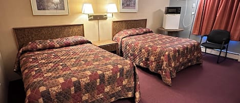 A hotel room with two beds, a nightstand, a lamp, a chair, and a wall-mounted air conditioner.