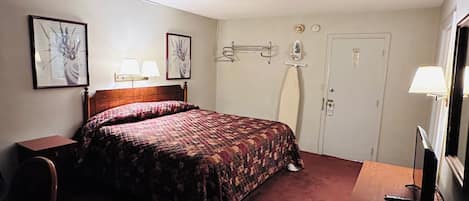 A hotel room with a bed, bedside tables, a desk, a chair, a TV, and wall-mounted lamps.