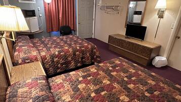 A hotel room with two beds, a desk, a chair, a TV, a mirror, and a lamp.