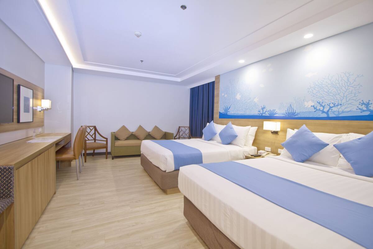 Ein Hotelzimmer mit zwei Betten, einem Schreibtisch und einem Stuhl.