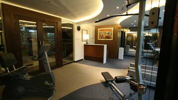 A gym with cardio equipment, a reception desk, and a painting on the wall.