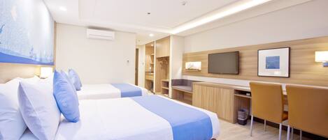 A hotel room with two beds, a desk, and a chair.