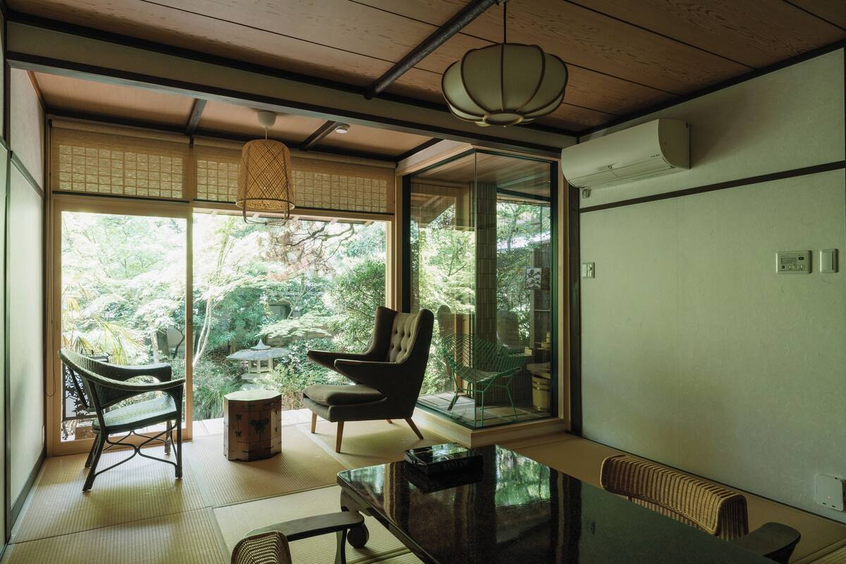 A traditional Japanese room with tatami flooring, a low table, and two chairs.