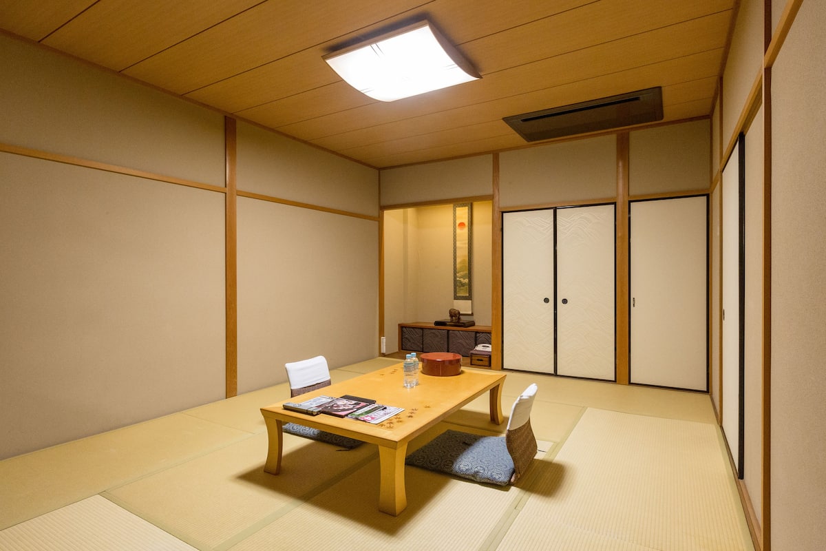 A traditional Japanese room with tatami flooring, a low wooden table, and a tatami mat chair.
