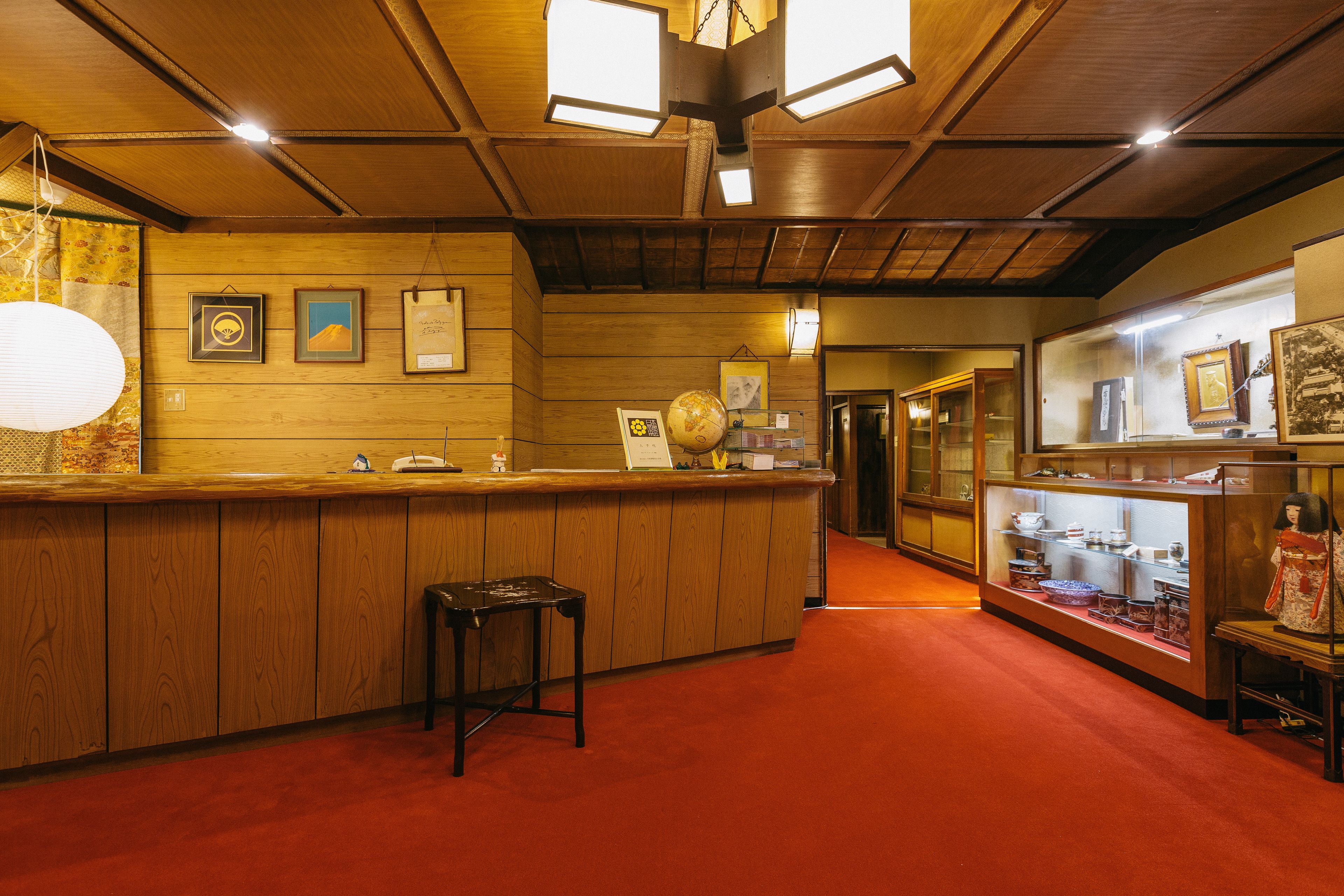A wooden interior with a reception desk, a globe, and various framed pictures on the wall.