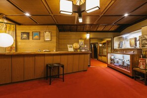 A wooden interior with a reception desk, a globe, and various framed pictures on the wall.